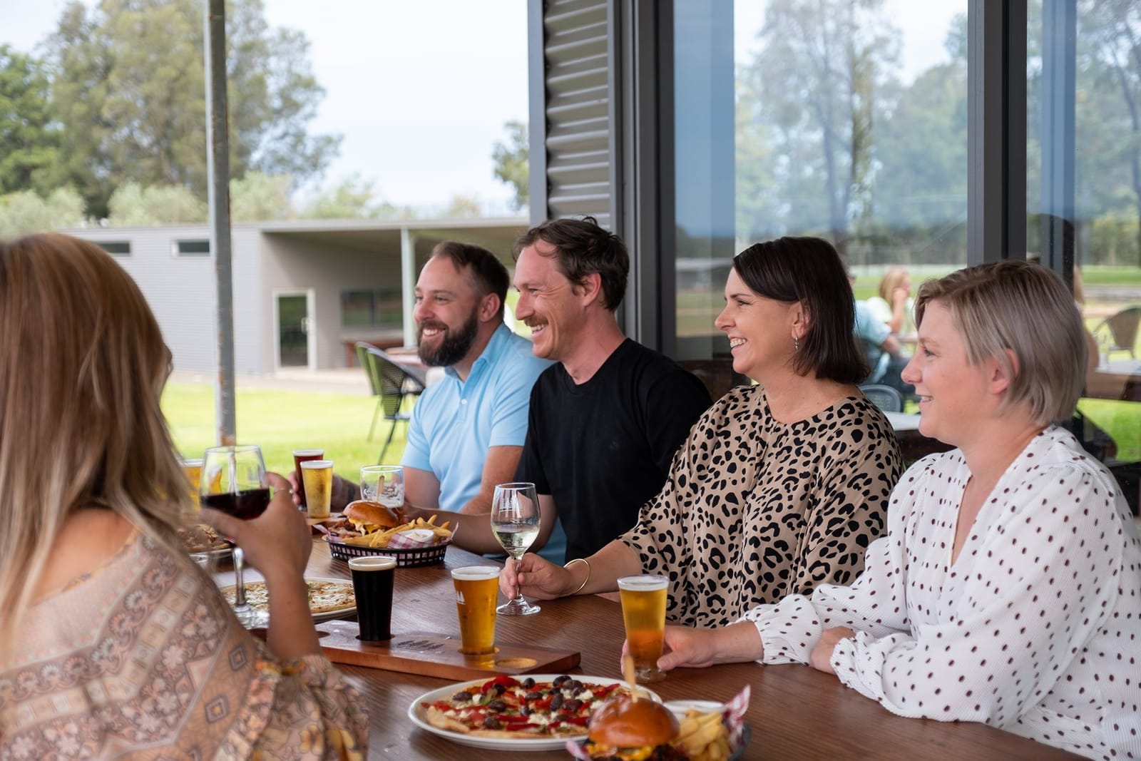 Friends sharing pizzas, burgers and beer paddles at the Barrel Bistro