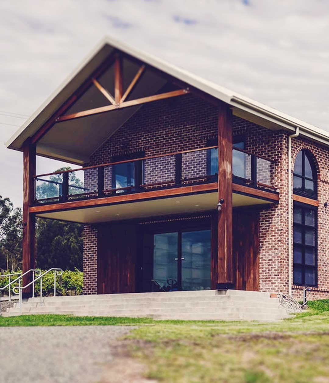 Two storey brick cellar door building with red timber accents at Adam's Leap, Pokolbin, Hunter Valley