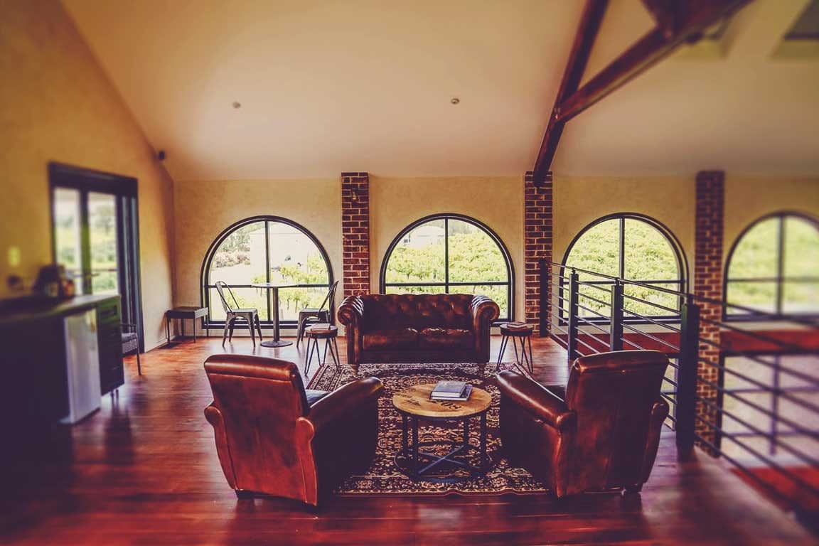 Cellar door lounge with burgundy leather seating and vineyard views