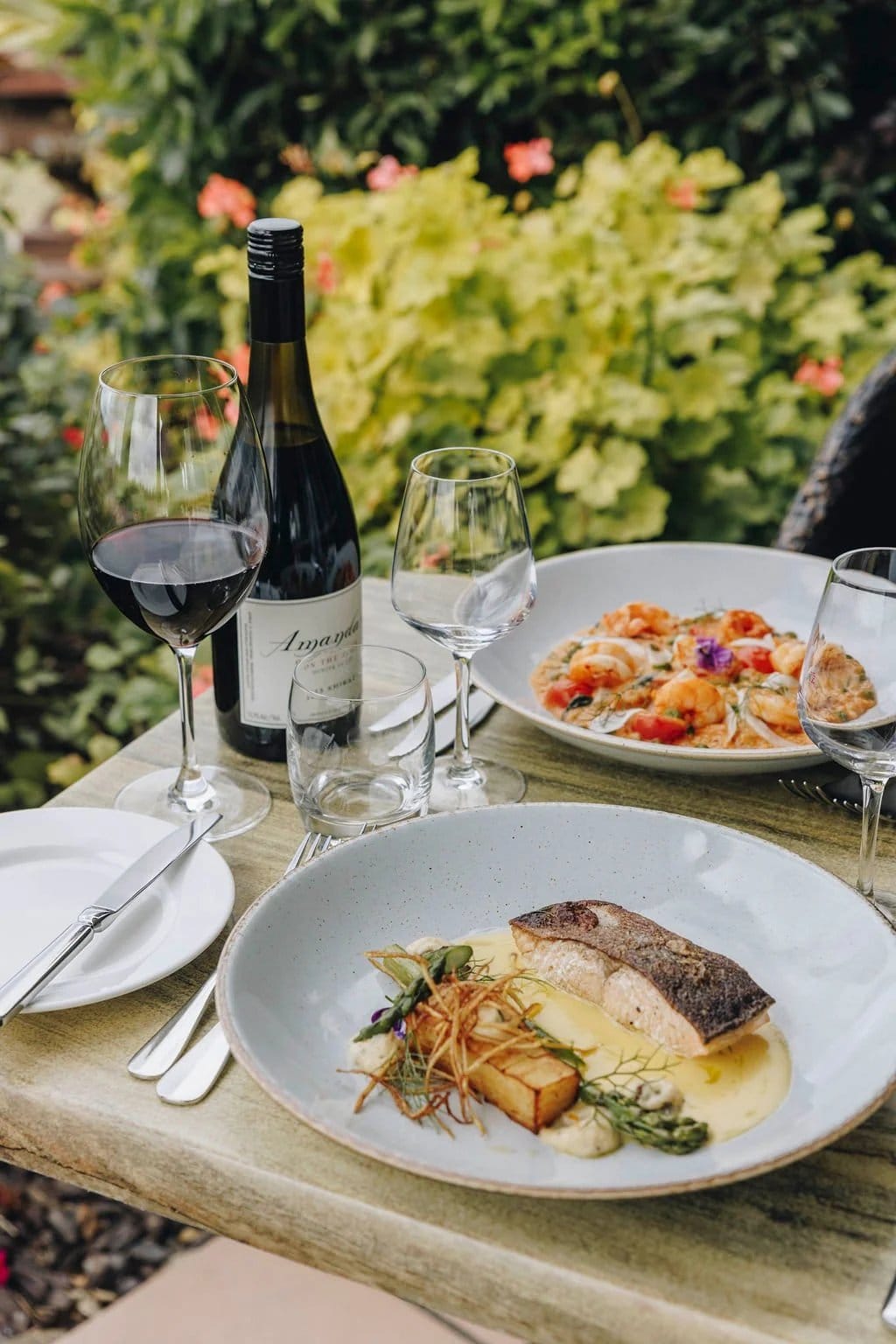 A plated main course with a glass of red wine on the table