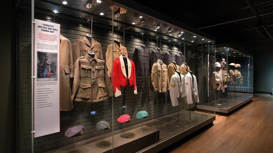 A long glass case of infantry uniforms and berets from several eras