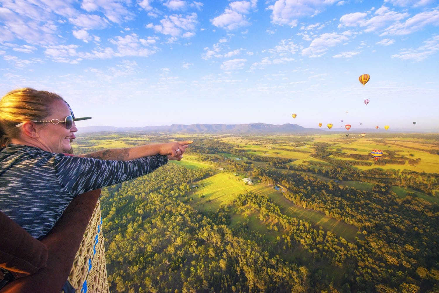 Visitor in hot air balloon with other balloons and landscape below at Balloon Aloft, Pokolbin, Hunter Valley