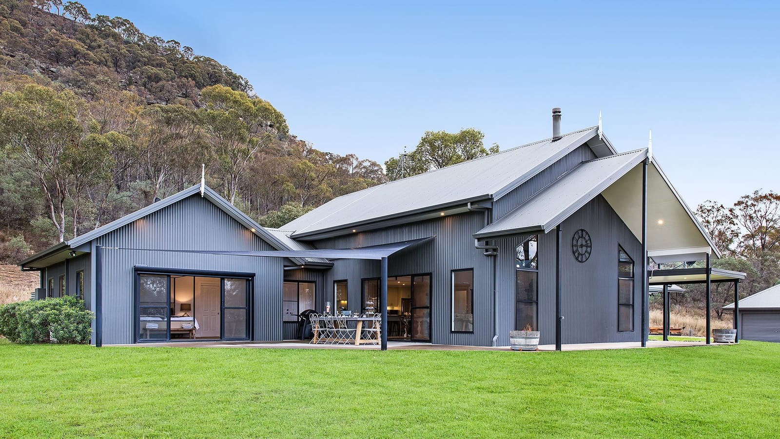 Modern steel-clad guest lodge with verandah and hillside forest
