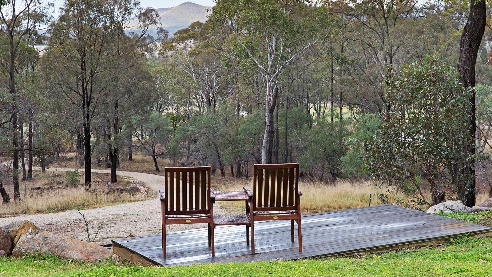 Wooden chairs on deck overlooking forested property and mountains