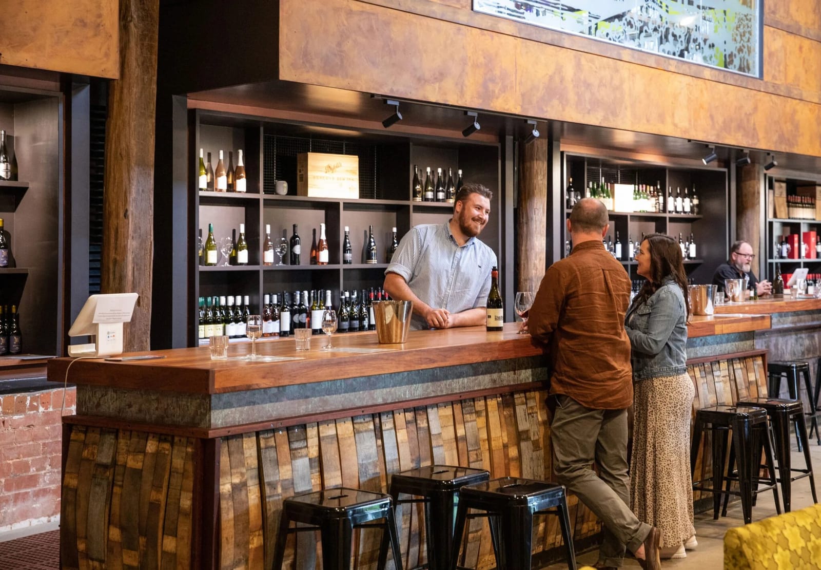 Wine tasting bar with staff member and bottles on timber counter