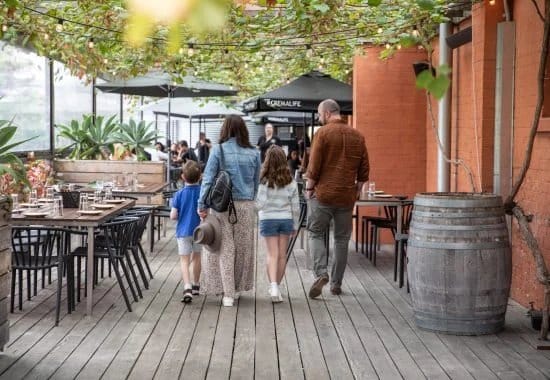Covered outdoor dining with timber floor and wine barrel planter