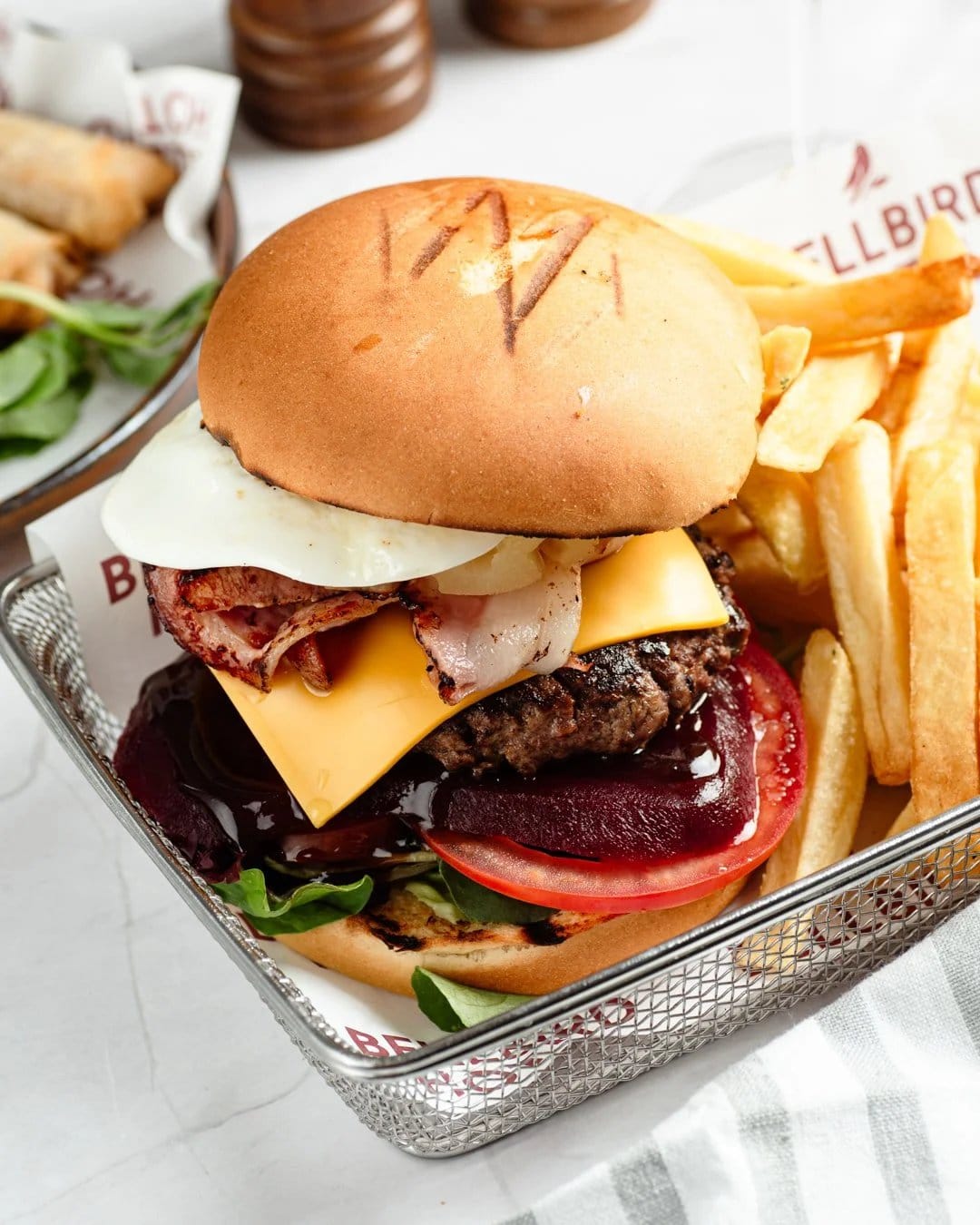 Gourmet burger with bacon and crispy fries served on plate