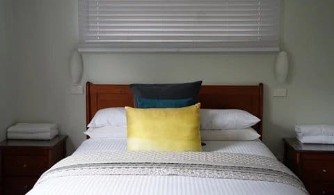 Bedroom with red and gold cushions on wooden headboard at Beltana Villas, Pokolbin, Hunter Valley