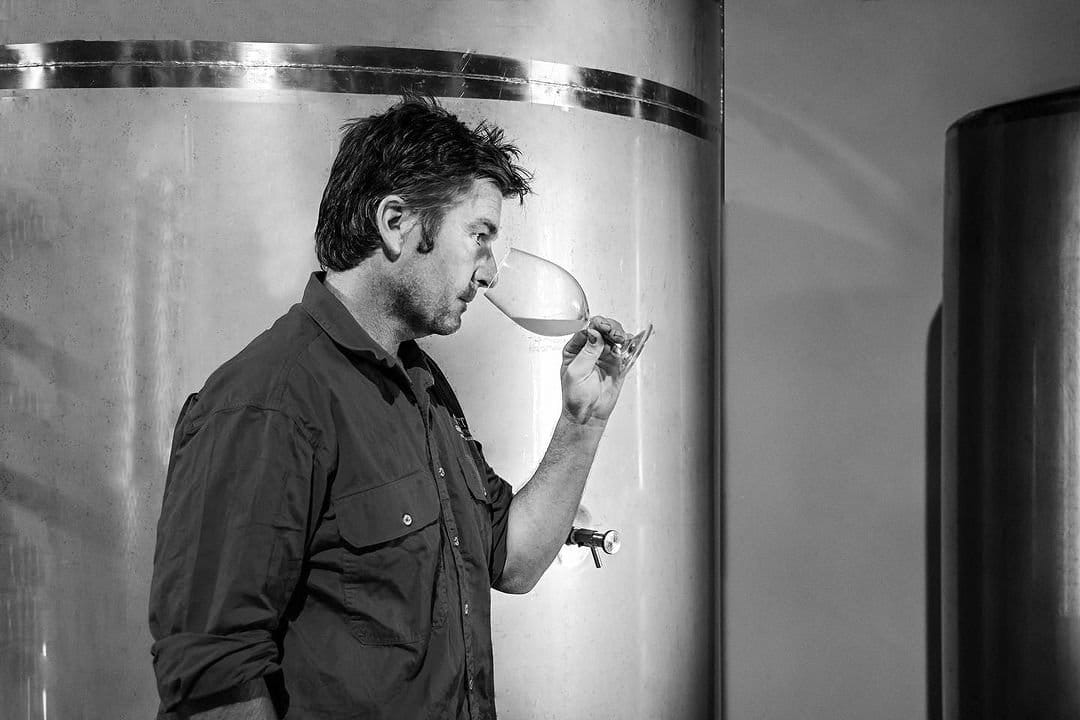 Winemaker tasting wine from barrel in fermentation space