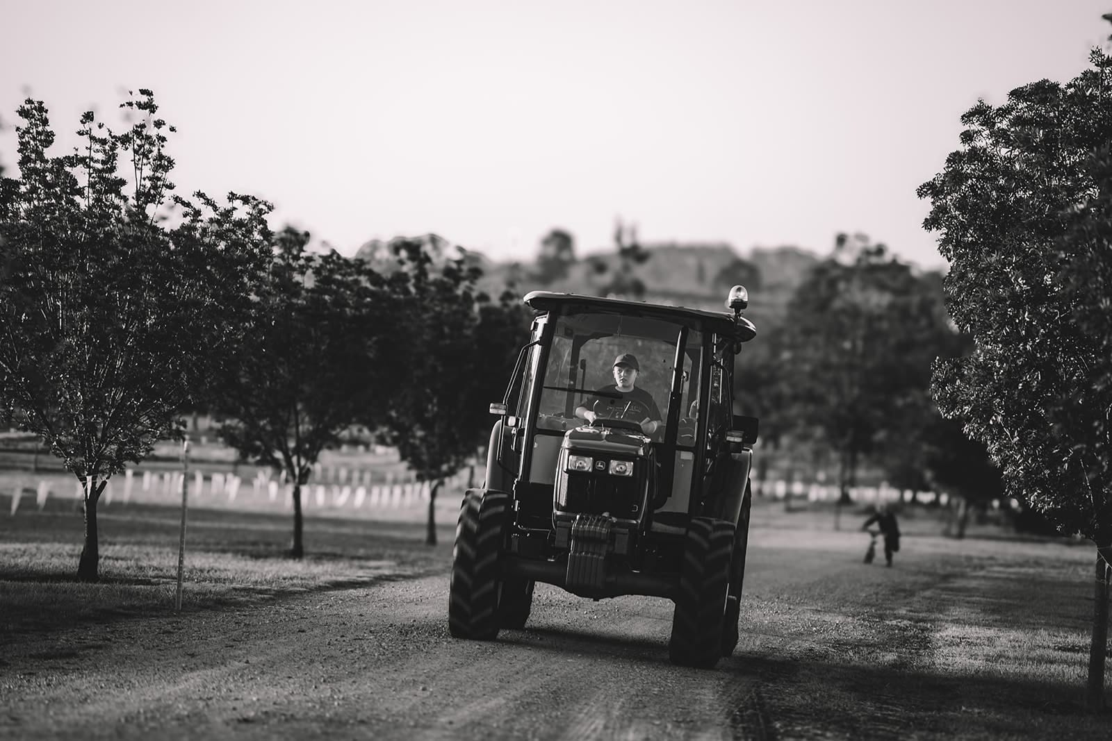 Tractor driving through vineyard grounds with tree-lined pathways