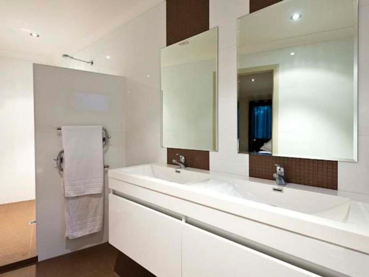 Contemporary ensuite bathroom with double vanity and neutral tiles