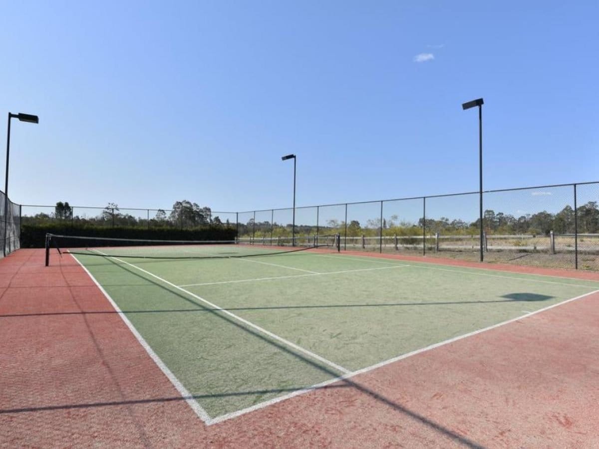 Tennis courts with manicured surface and surrounding trees