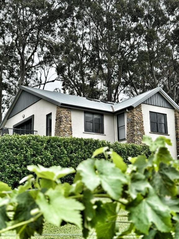 White and stone guest cottage with manicured hedges