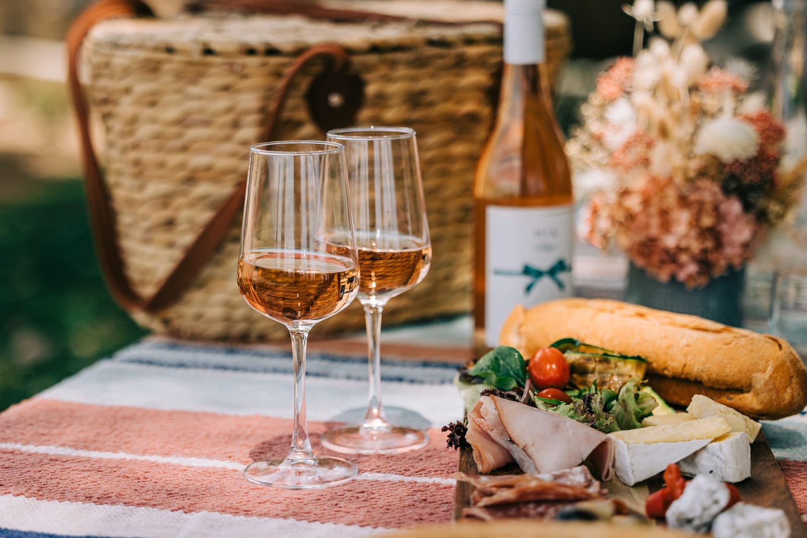 Rose wine with outdoor picnic setup and fresh flowers