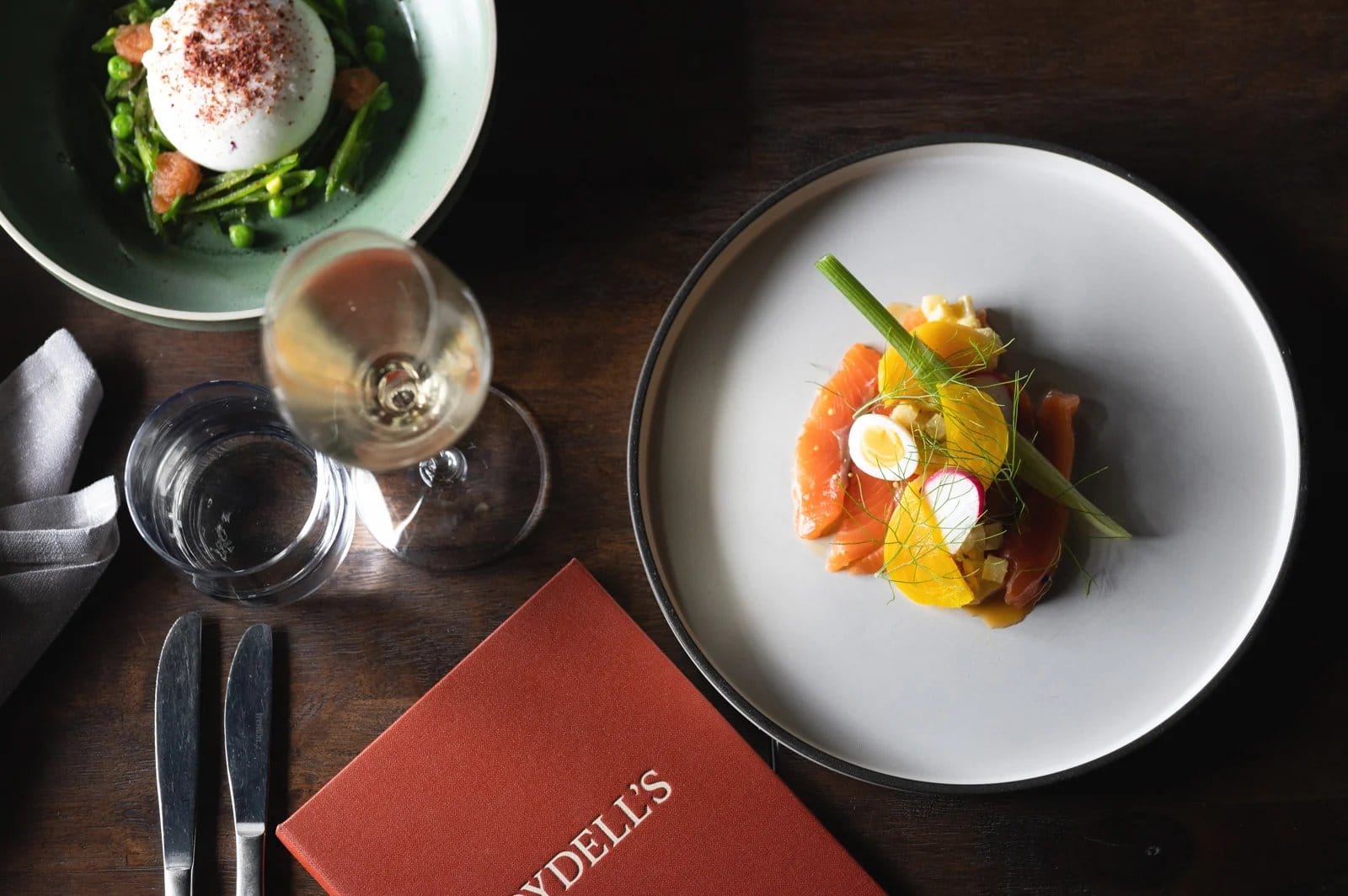 Fine dining dishes with fresh salads and wine pairing on table