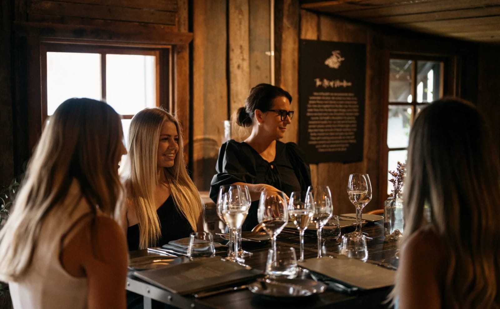 Group dining at long table in timber-lined tasting room with wine