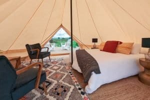 Inside a glamping bell tent, bed made up and a rug on the floor