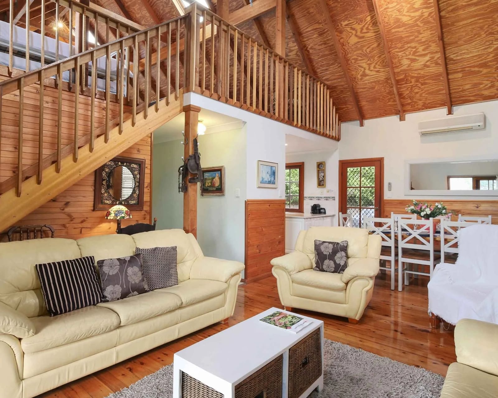 The cottage's living area with the family loft above, leather sofas and a dining table.