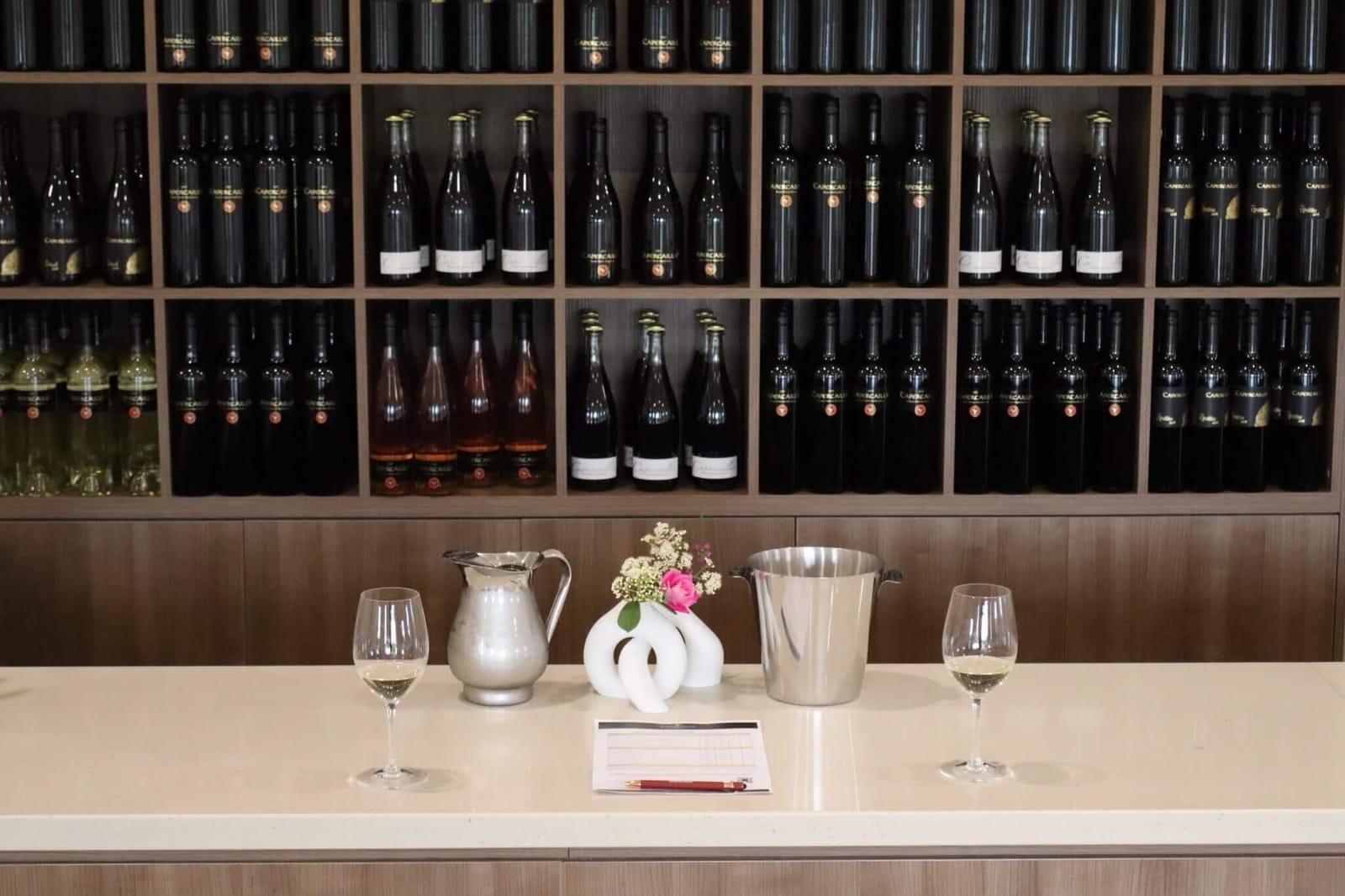 Wine bottles displayed on wooden shelving behind counter