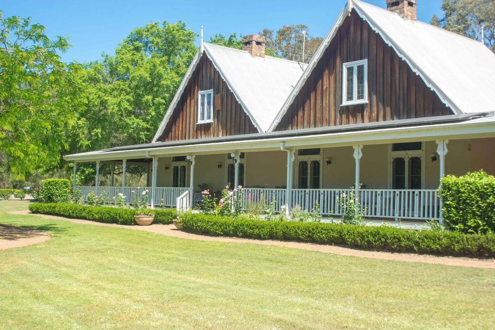Estate building facade with white porch and manicured hedges