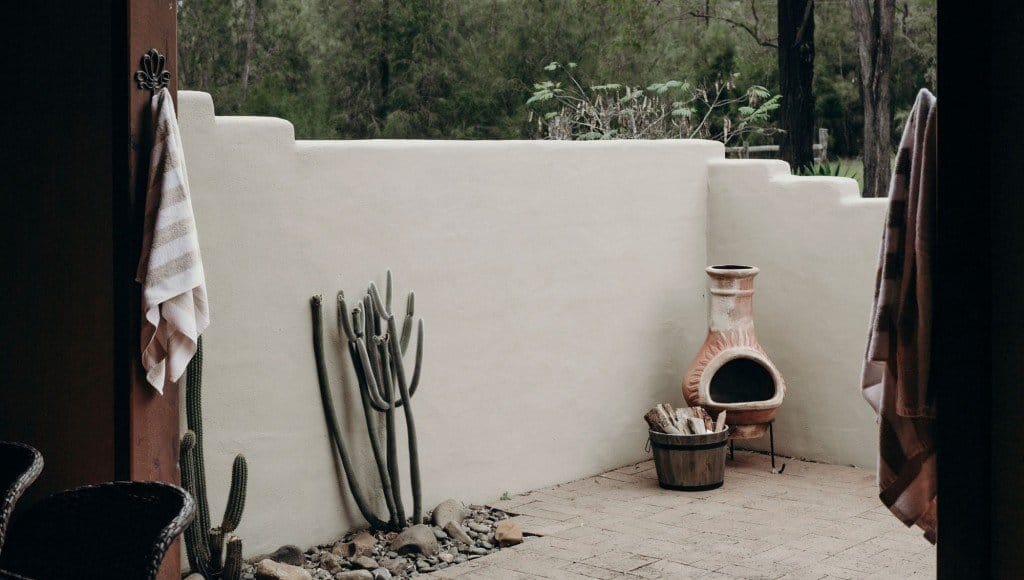 A walled courtyard with cactus and an outdoor fireplace