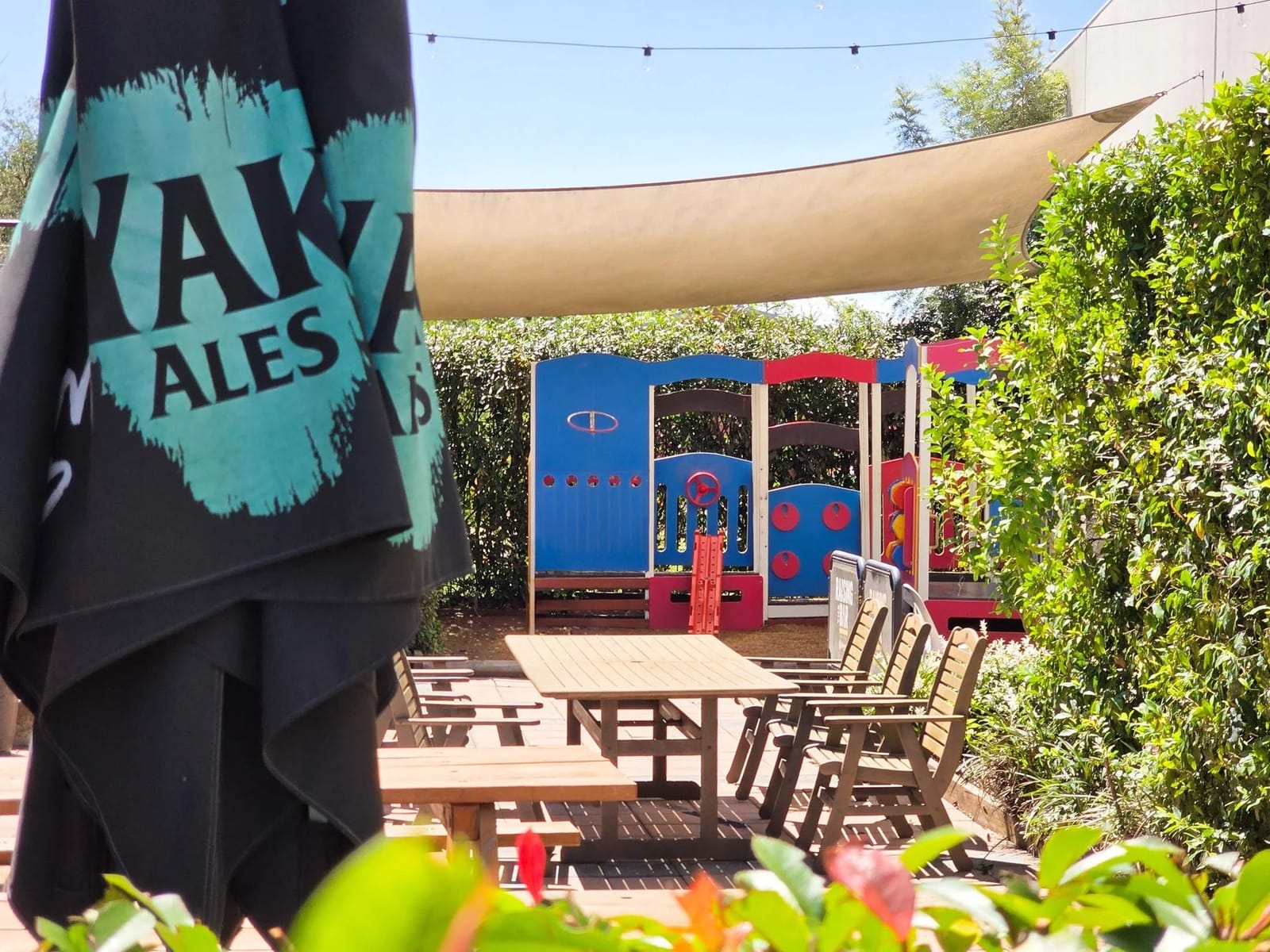 Outdoor beer garden courtyard with wooden tables, chairs and a shade sail at Cessnock Hotel.