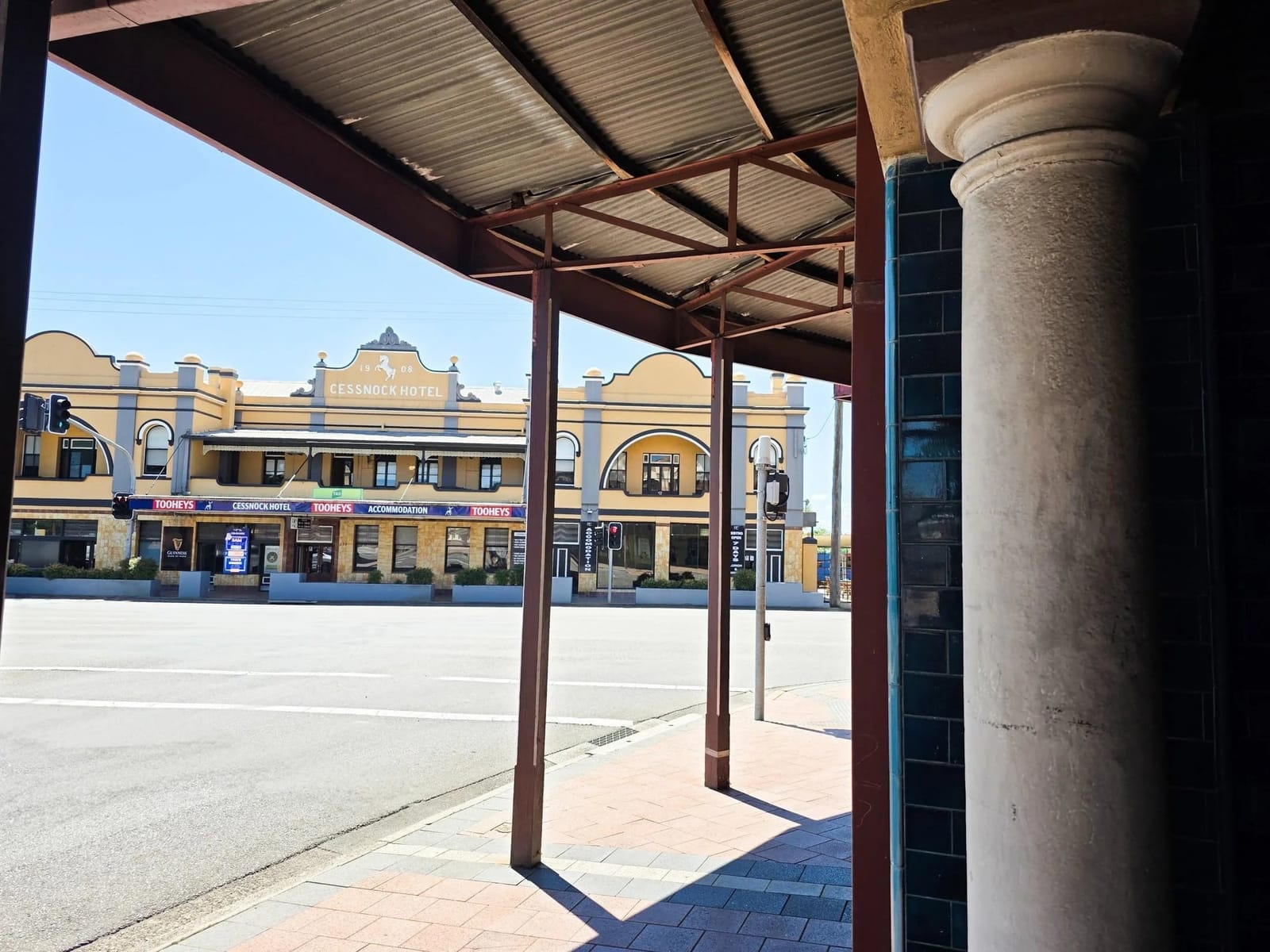 Two-storey brick hotel building on a Cessnock street corner, seen from under an awning across the road.