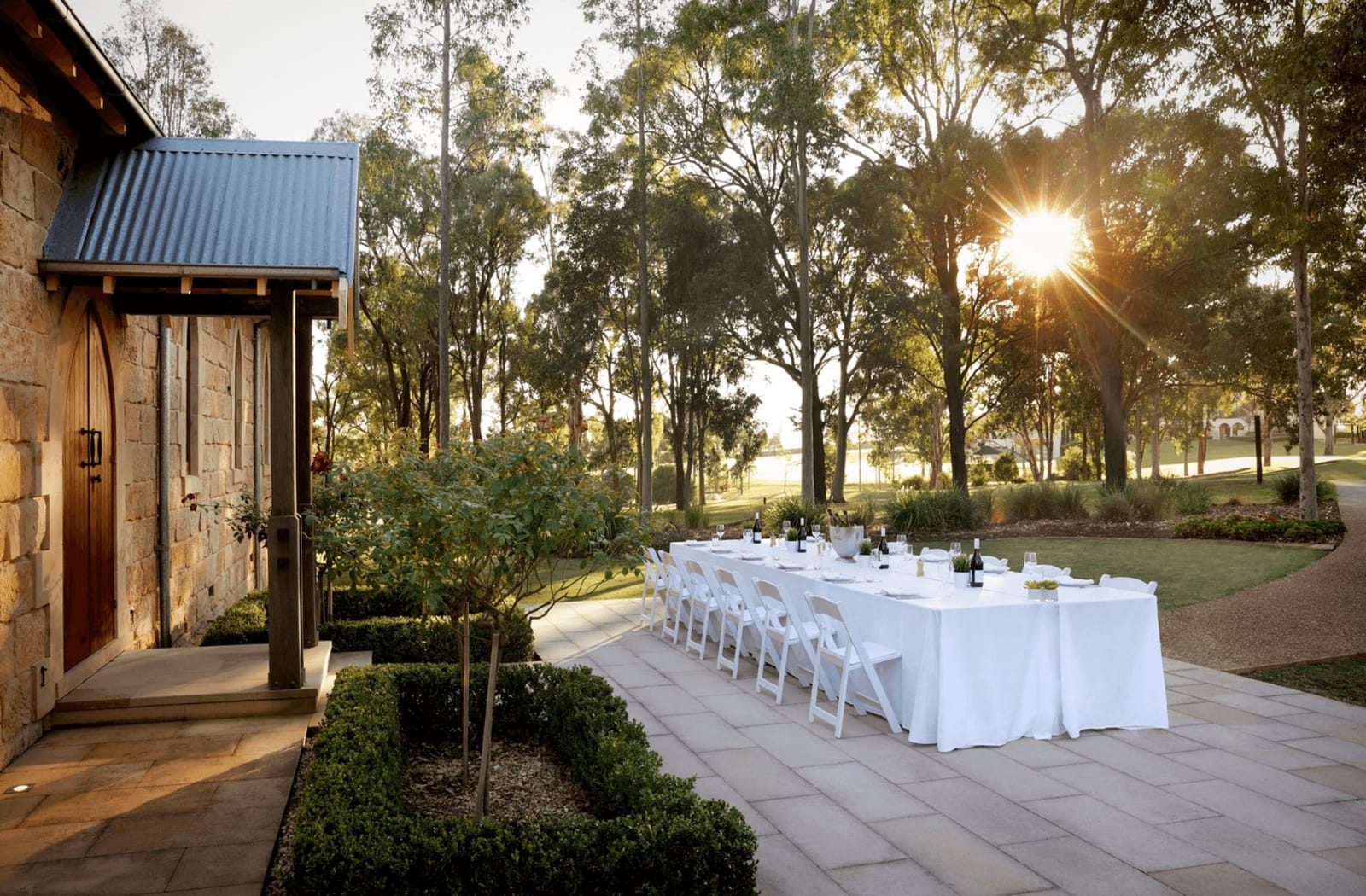 Long white table set for dinner beside the sandstone chapel at Chateau Elan at The Vintage, Pokolbin, Hunter Valley