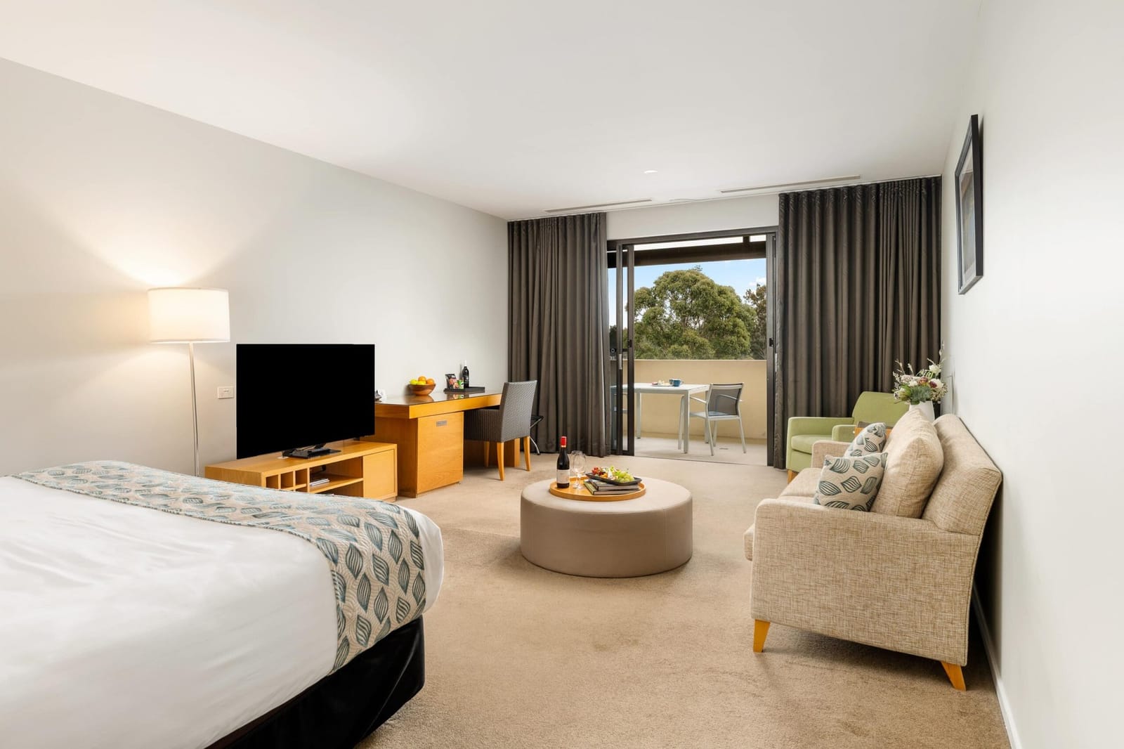 A Chateau Elan guest room with a king bed, lounge and sliding doors onto a private balcony