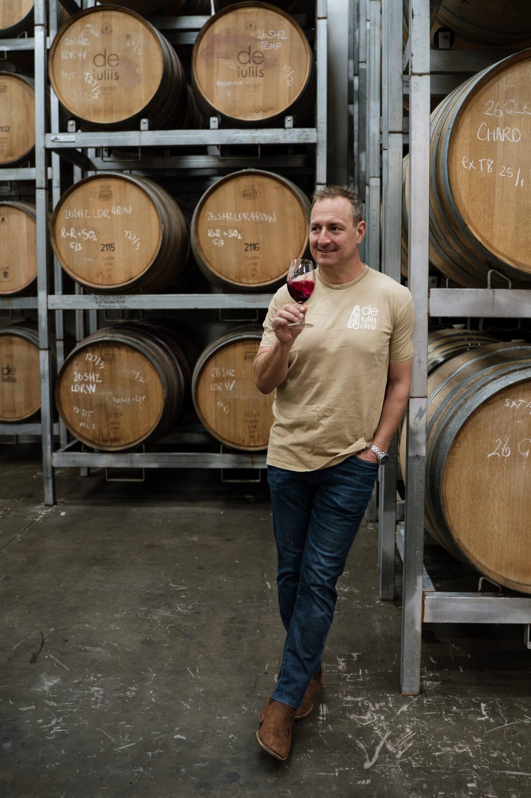 Winemaker in barrel room holding red wine for tasting