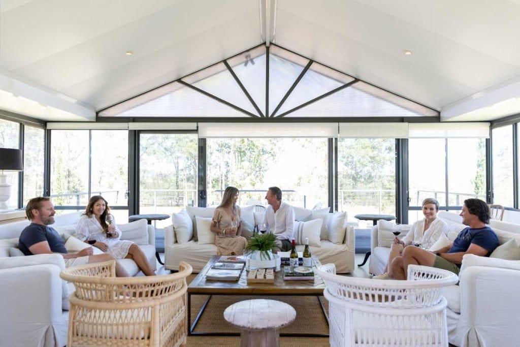 Guests with wine glasses in the light-filled summer house lounge at Degen, Pokolbin, Hunter Valley