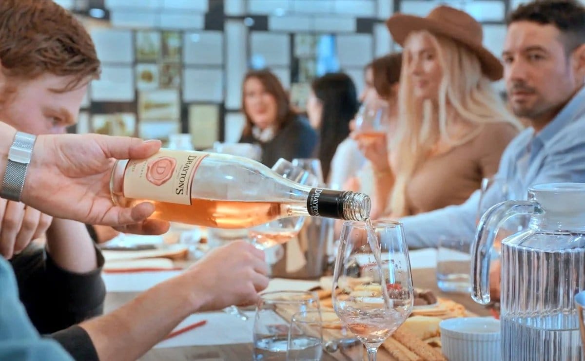 A group seated at a long table with wine and food