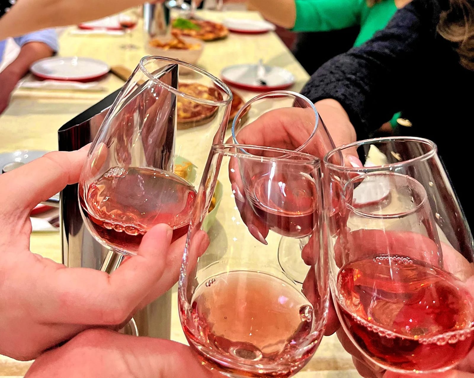 Hands raising glasses of rose at a tasting