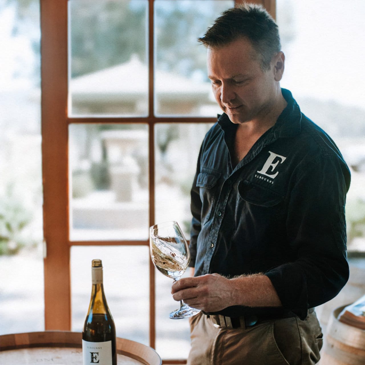 Staff member holding wine glass with landscape visible through windows