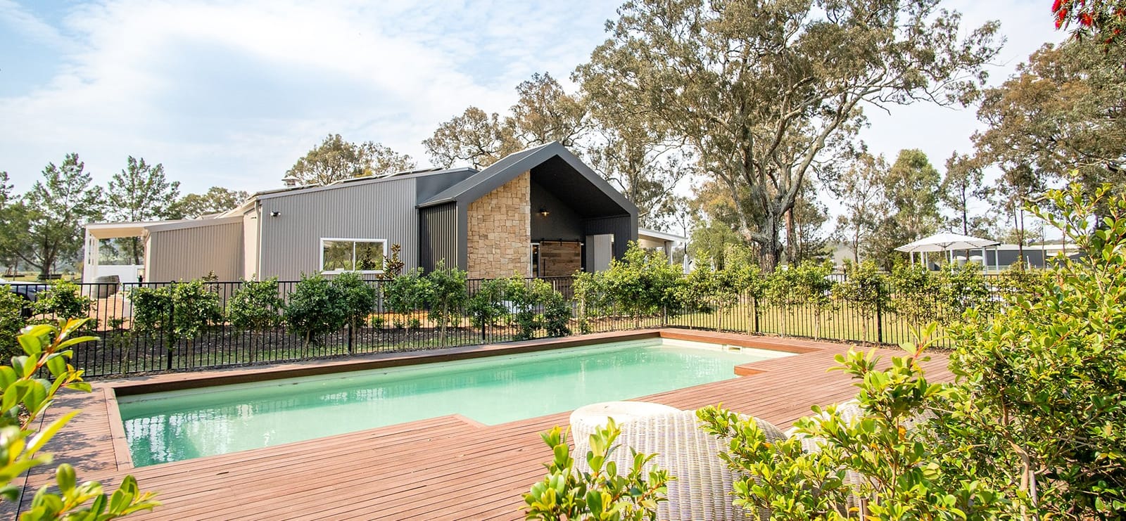 Swimming pool with timber decking, modern lodge and vineyard setting
