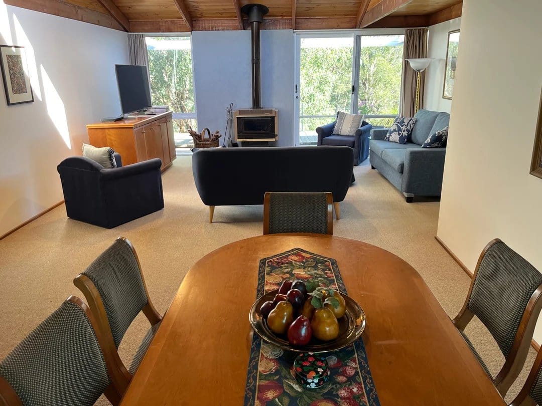 Upscale lounge with stone fireplace, grey seating, wooden ceiling and vineyard views through tall windows