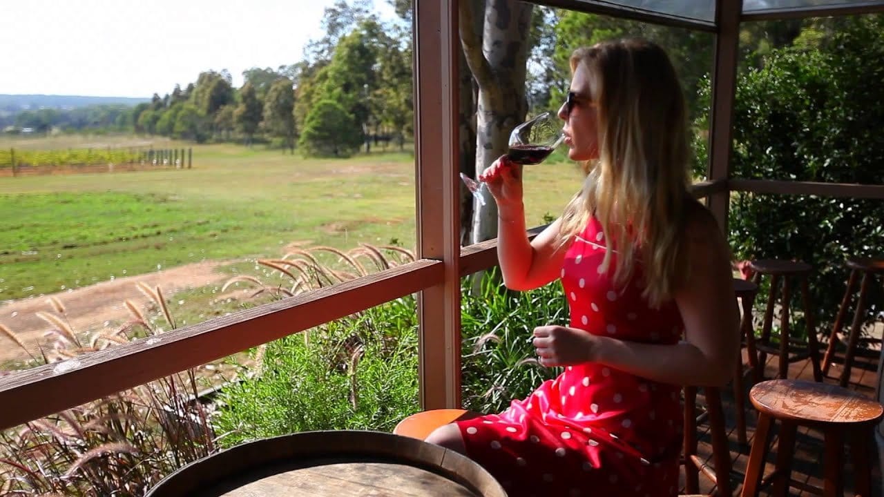 A visitor with a glass of red on the Ernest Hill verandah, looking out over the vineyard