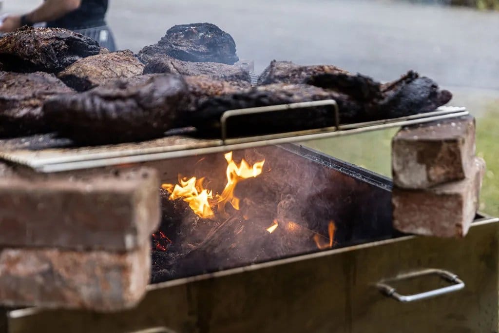Meat grilling over an open flame in the Estancia Adina kitchen