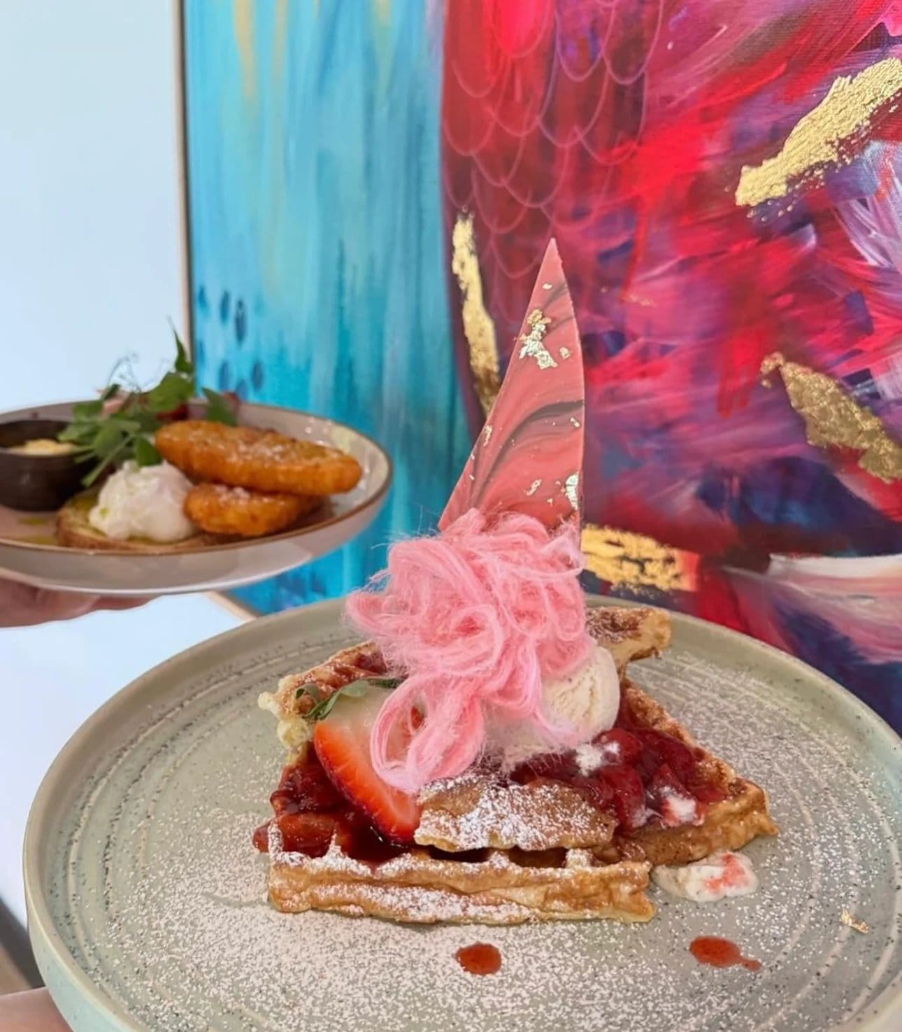 A waffle dessert with strawberry compote, cream and spun sugar on a plate at Flock & Fork.