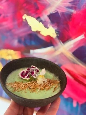 A green smoothie bowl topped with toasted coconut and edible flowers at Flock & Fork.
