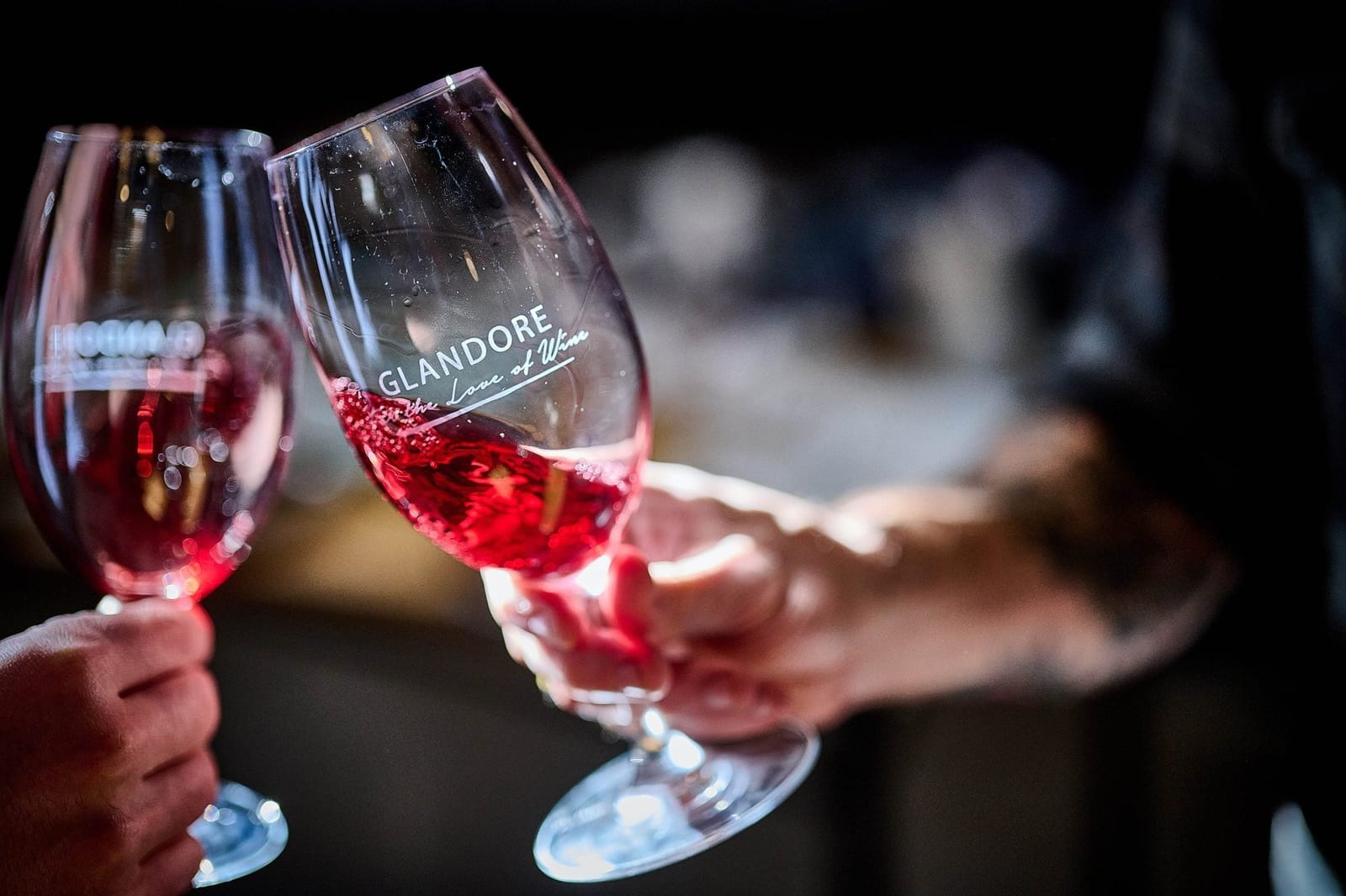 Two Glandore wine glasses with red wine held together for a toast