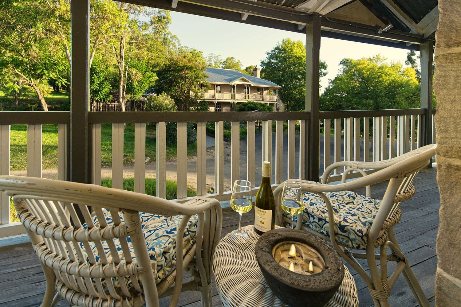 Verandah view with wine glasses and seating overlooking the homestead grounds at Grays Inn Wollombi, Wollombi, Hunter Valley