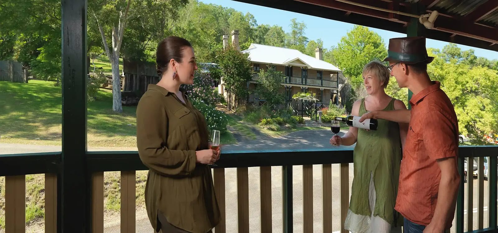 Guests tasting wine on the verandah with the estate homestead in view