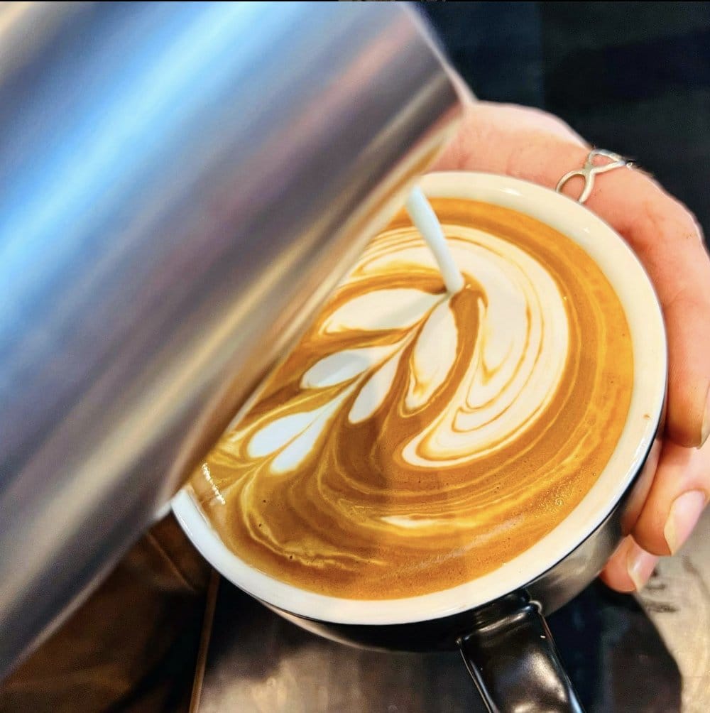 A flat white being finished with latte art at Greg's Espresso Bar
