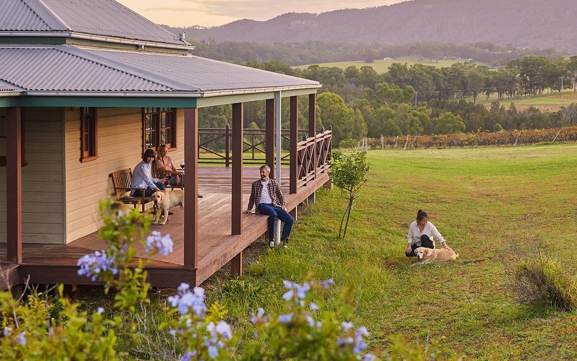 Guest cabin with verandah seating overlooking vineyard landscape and mountains