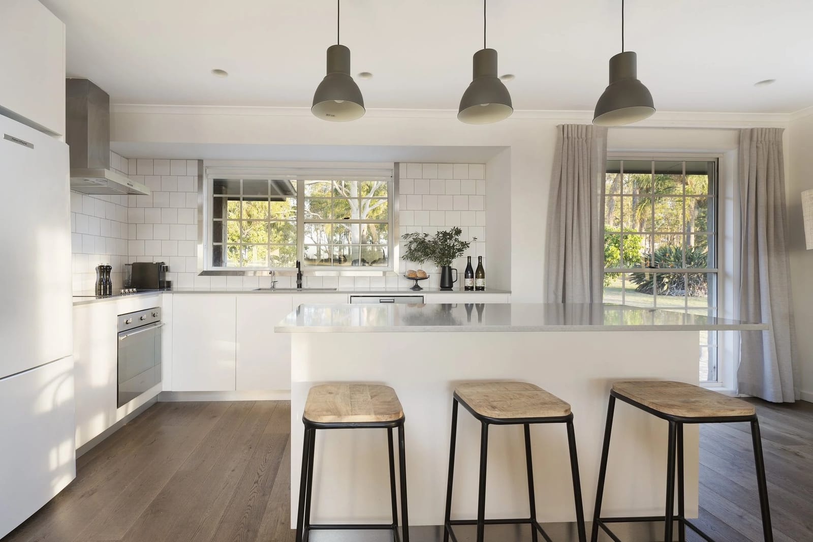 Modern kitchen with white cabinetry, island bench and window views