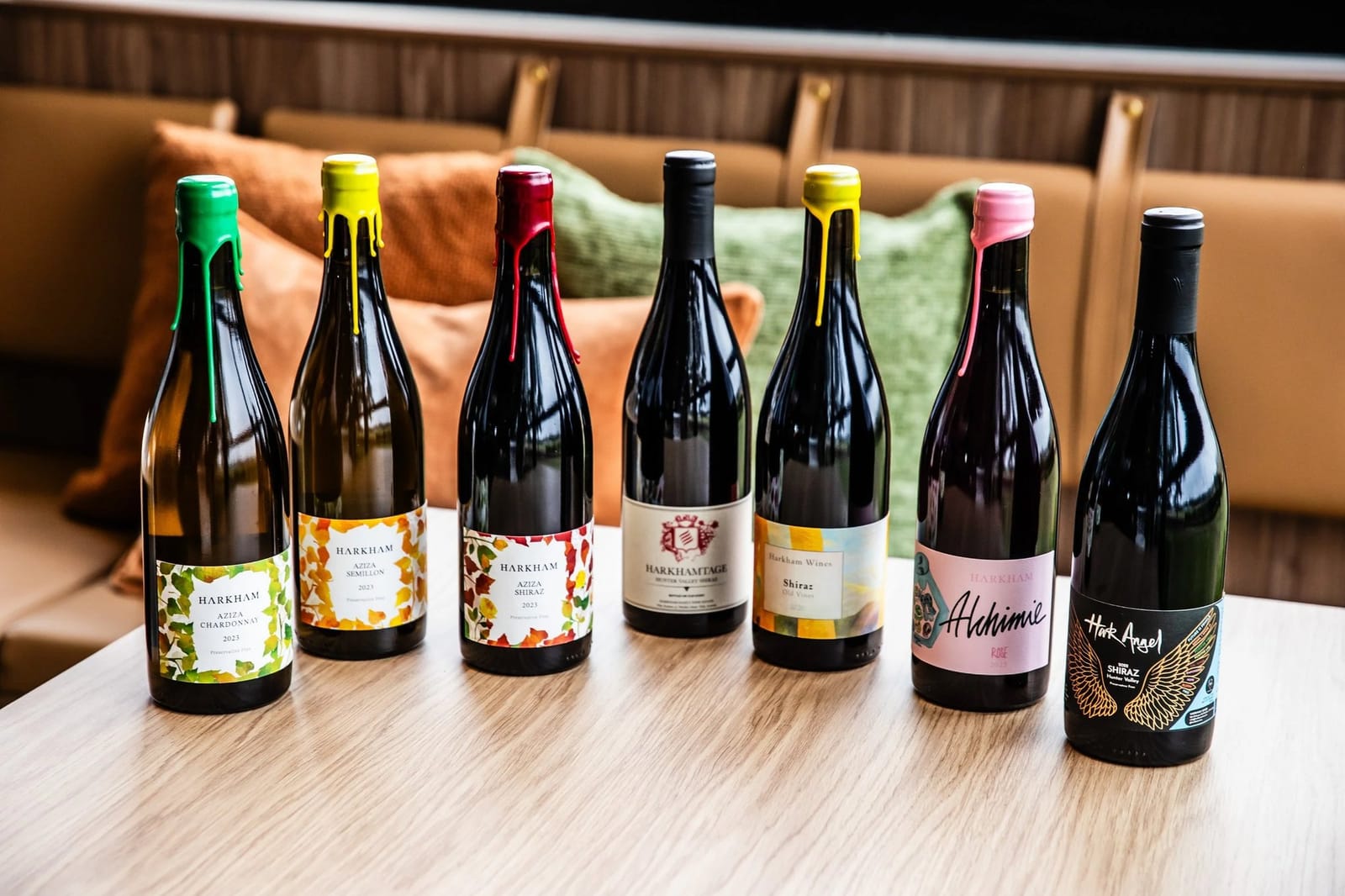 Seven wine bottles with colourful labels displayed on a table