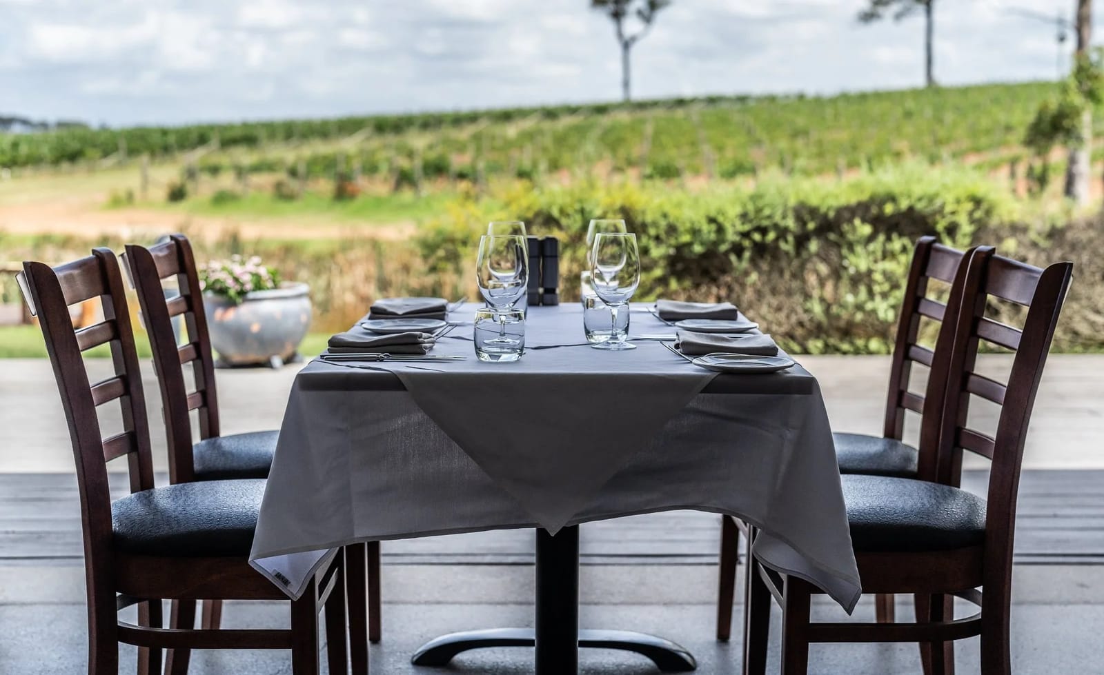 Outdoor dining table set for four on the Harvest terrace, looking across the RidgeView vineyard.