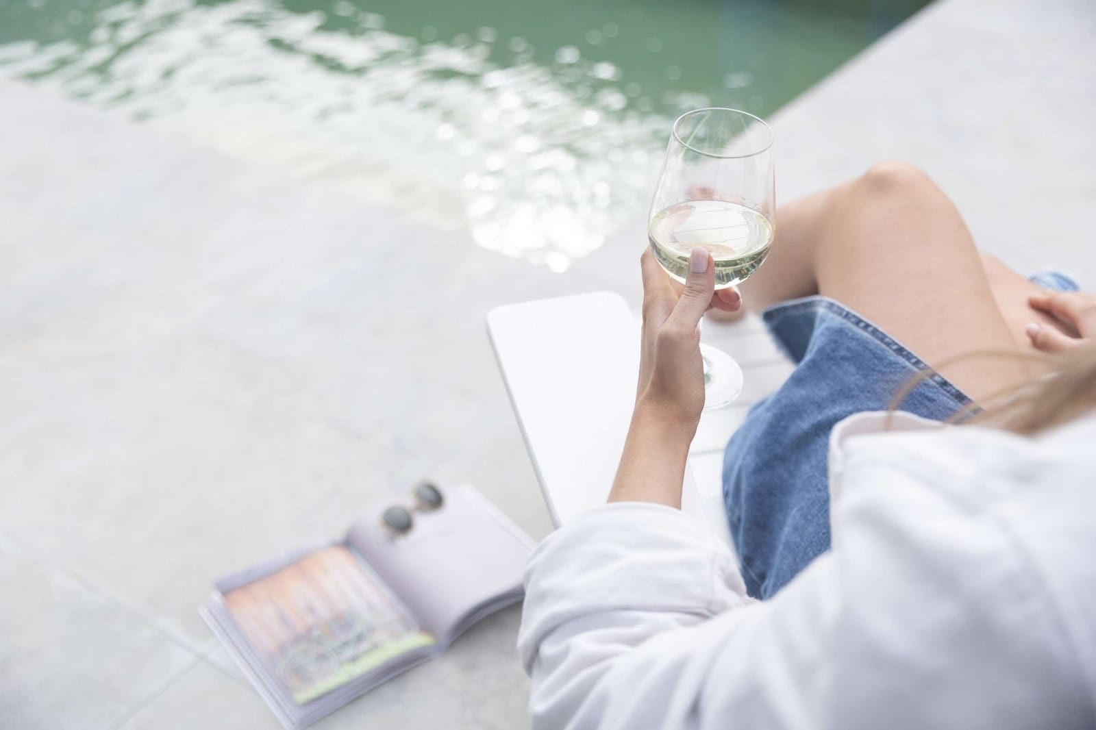 Guest holding wine glass by the swimming pool edge