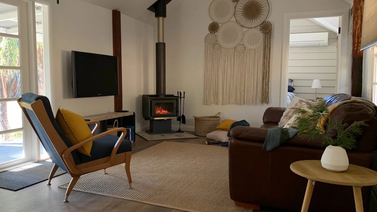 Cosy living room with a wood fire and macrame wall hanging at Hollybrook, Wollombi, Hunter Valley